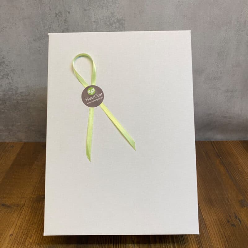 White gift bag with a pale green ribbon loop and a circular NaturGuet tag on the front edge of the bag.